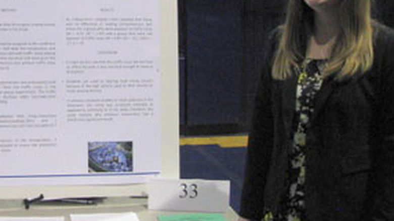 Alicia Carson beside poster at research fair