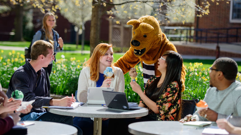 Lion mascot with four students sitting at table