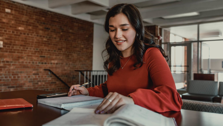 Student sitting at table with books and calculator