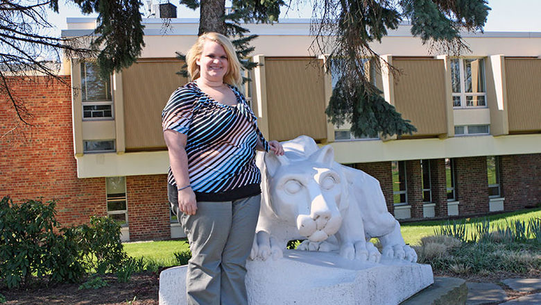 An Administration of Justice alumna stands next to the campus lion shrine