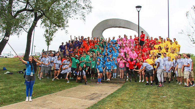 Students posing for a photo by the campus arch