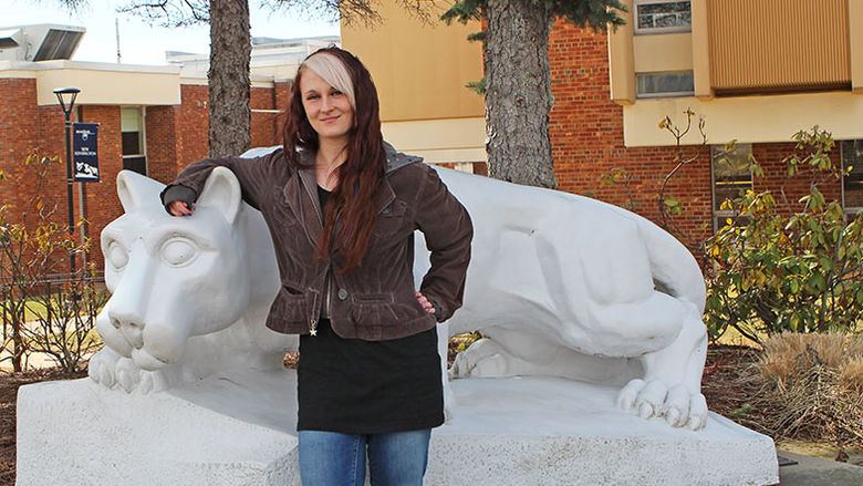 An Administration of Justice alumna stands next to the campus lion shrine