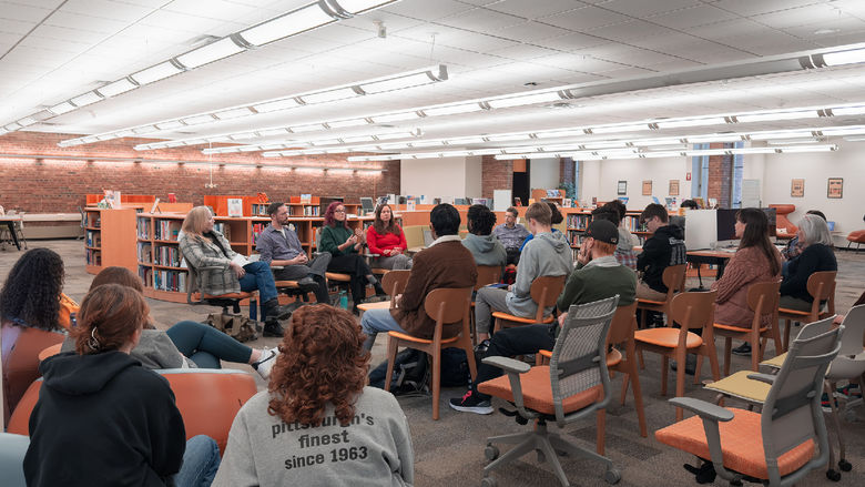 Students and guests listen to faculty speaking panel in library