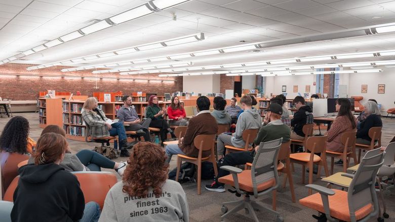 Students and guests listen to faculty speaking panel in library