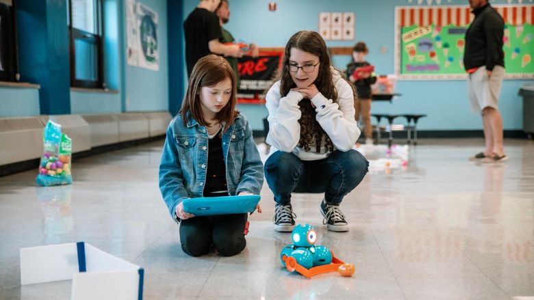 College student helps elementary school student with robot