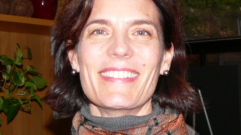 Sara Curran headshot in grey sweater, orange scarf.