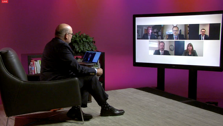 Kevin Snider sits and looks at virtual panelists on television screen