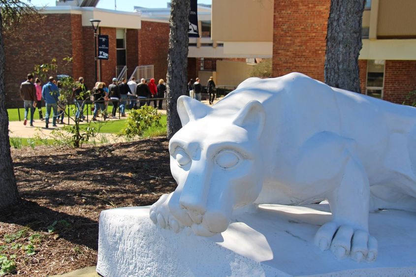 Tour group passes behind lion shrine at Penn State New Kensington