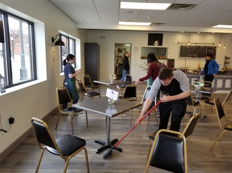 Students sweep floors and clean area of Knead Cafe