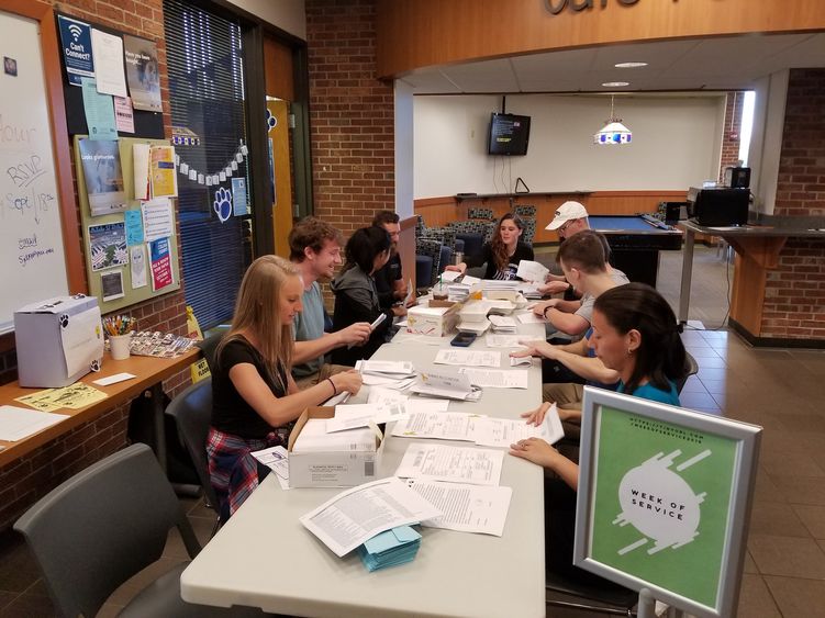 Students stuffing envelopes at table