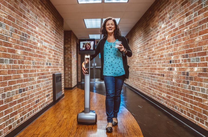 Penelope Morrison walks down a hall with Kristal Tucker projecting herself through the Beam robot