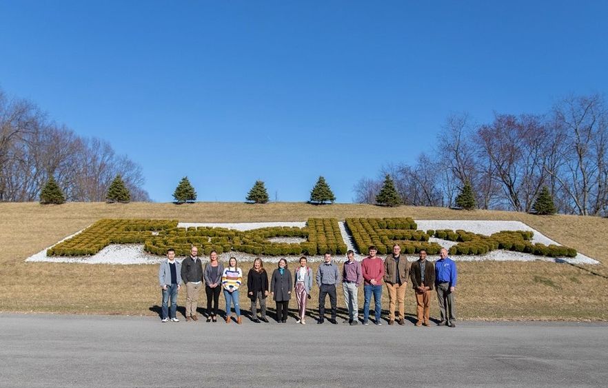 Group stands in front of bushes that spell out FedEx