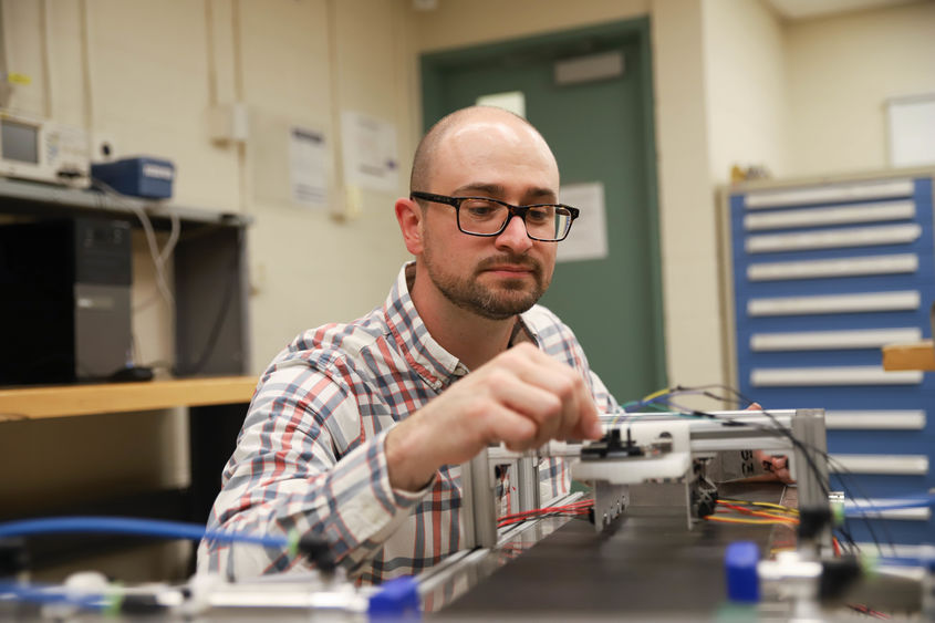 Joseph Cuiffi wiring conveyor belt in lab