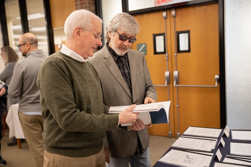 Dr. Harnish and Dr. Bridges stand while looking at book