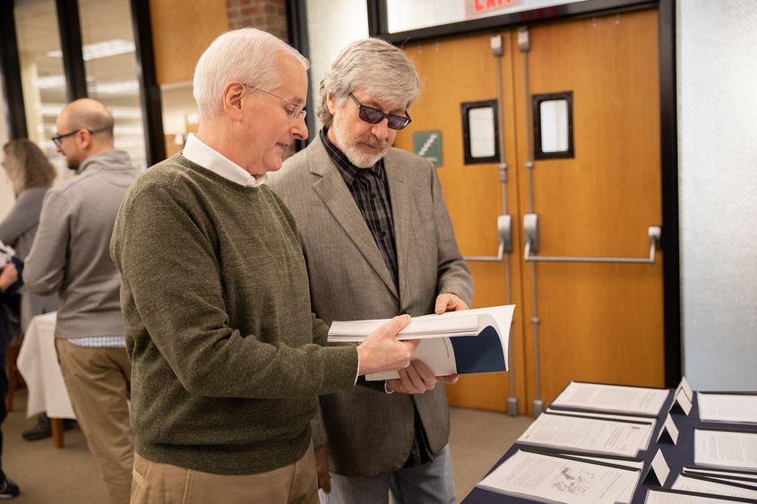 Dr. Harnish and Dr. Bridges stand while looking at book Dr. Harnish and Dr. Bridges stand while looking at book