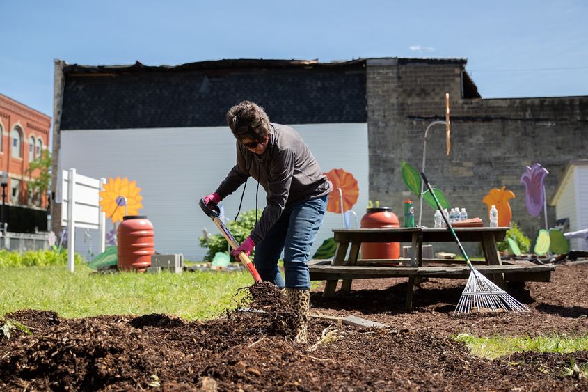 Woman shovels mulch at community garden