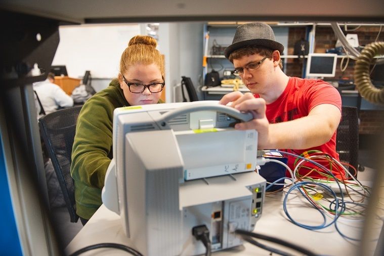 Two students work on hospital equipment in lab Two students work on hospital equipment in lab
