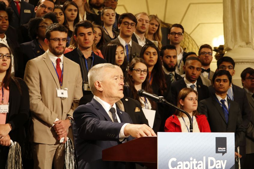 man at podium with students standing behind him