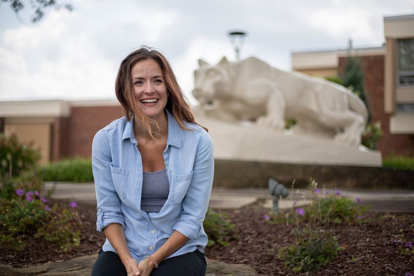 Woman sits in front of Nittany Lion Shrine