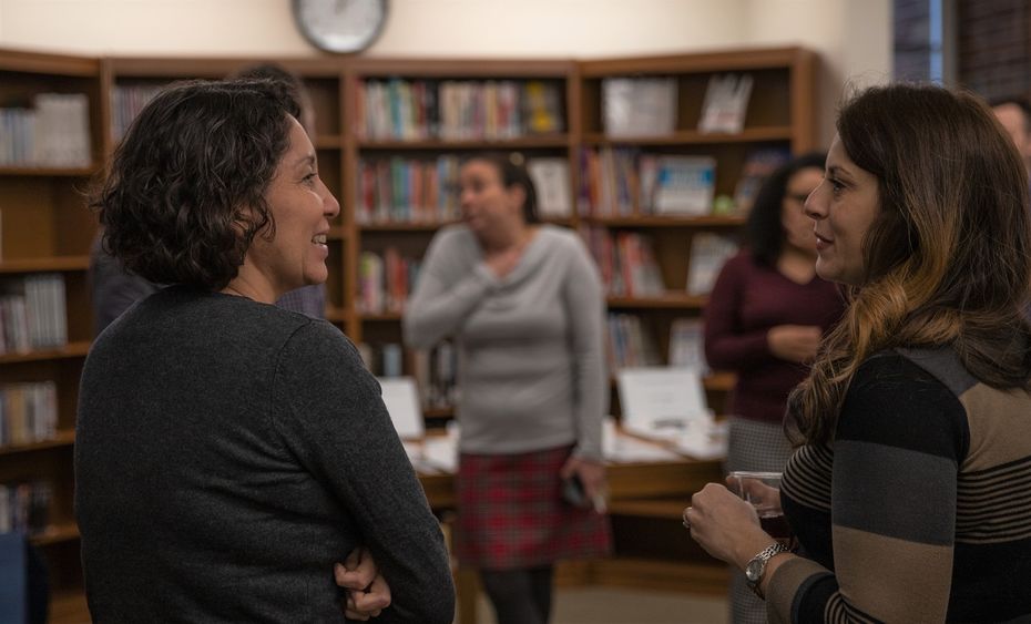 Two women stand and talk in library