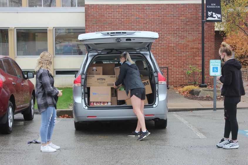 Student loads food donations into car Student loads food donations into car