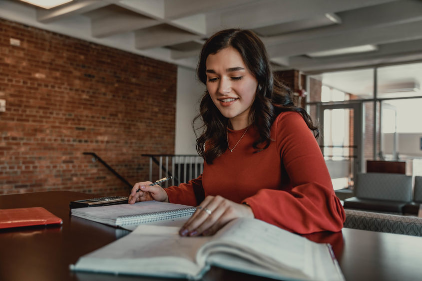 Student sitting at table with books and calculator