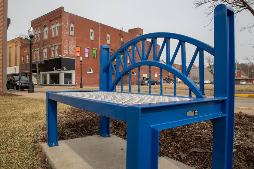 A blue bench along the sidewalk in New Kensington