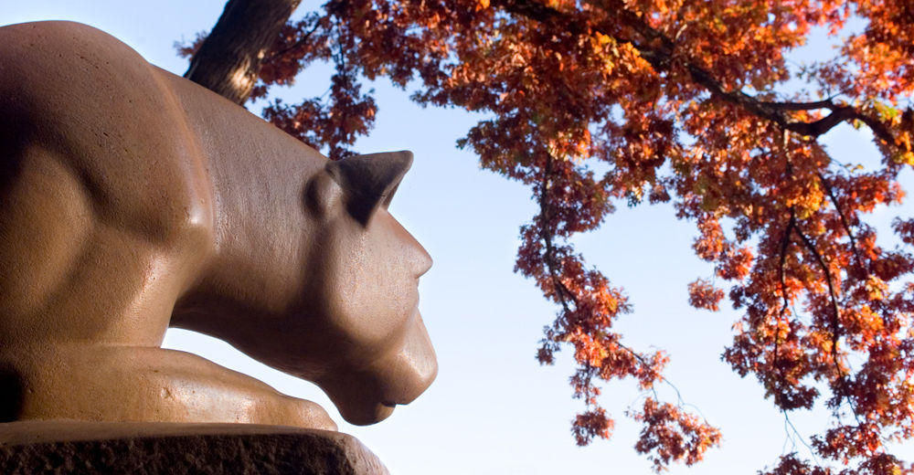 Nittany Lion Shrine with red fall leaves overhead.