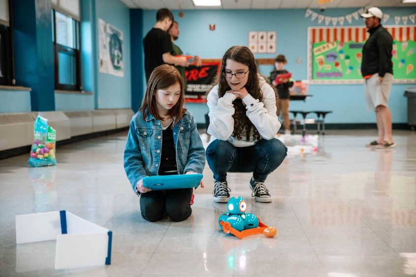 College student helps elementary school student with robot